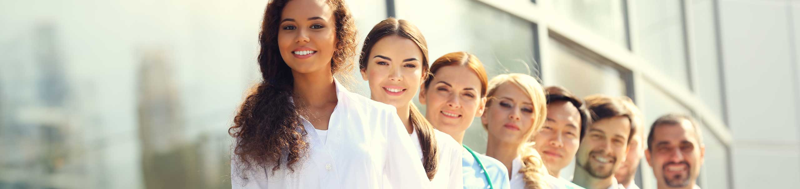 Smiling and diverse healthcare professionals standing in unity outside a modern facility, representing the compassionate and culturally relevant care team at Mahogany Home Health and Hospice, with career opportunities in Greater Cincinnati and Greater Dayton.